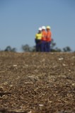 Mining Photo Stock Library - three mine site workers in full PPE in discussion.  workers out of focus.  vertical shot. ( Weight: 1  New Image: NO)