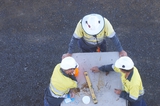Mining Photo Stock Library - construction safety meeting.  aerial photo of 3 workers in full PPE including hard hats and long sleeves having a safety meeting. could be on a construction mine site.  faces cannot be seen.  workers are drawing out designs. ( Weight: 1  New Image: NO)